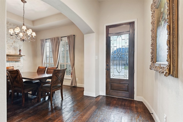 entrance foyer featuring a wealth of natural light, baseboards, arched walkways, and dark wood finished floors