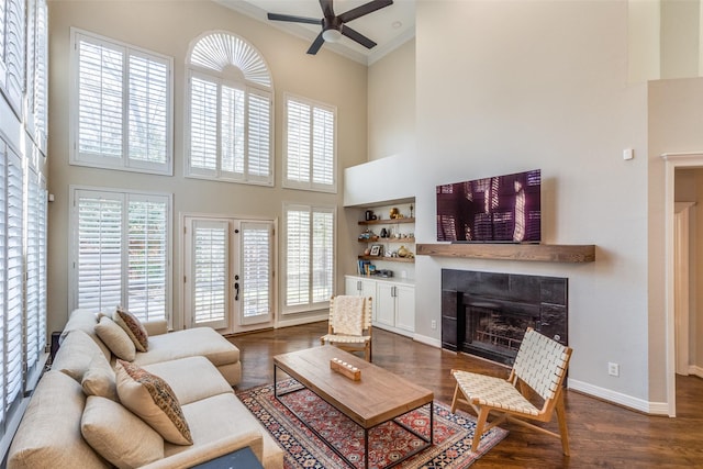 living room featuring french doors, a fireplace, baseboards, a towering ceiling, and dark wood-style flooring