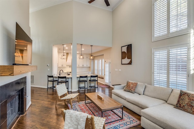 living room featuring visible vents, a fireplace, dark wood-style flooring, and ornamental molding