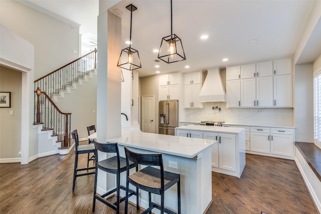 kitchen with dark wood-style floors, a kitchen island, high quality fridge, and premium range hood