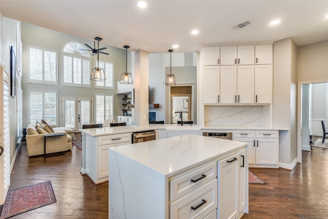 kitchen featuring dark wood-style floors, a peninsula, a sink, white cabinets, and dishwasher