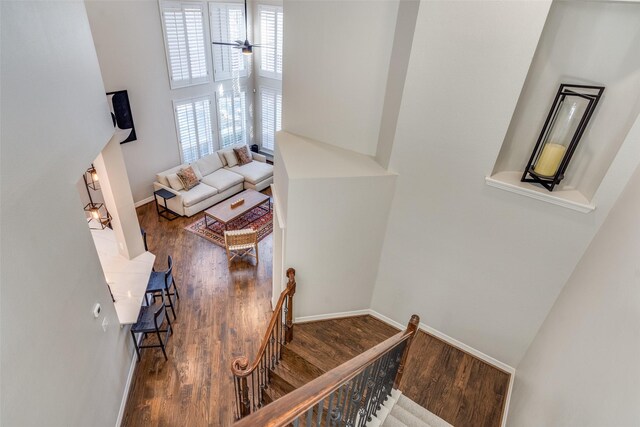 staircase with wood finished floors, baseboards, and a towering ceiling