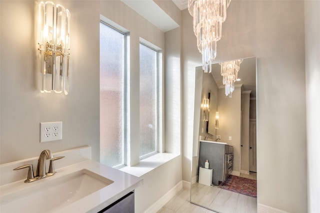 bathroom with a sink, baseboards, two vanities, and an inviting chandelier