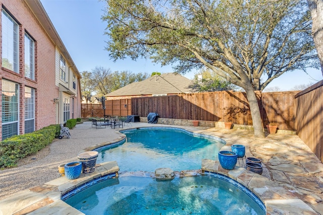 view of swimming pool featuring a pool with connected hot tub, a patio area, and a fenced backyard