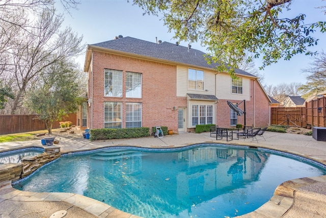 view of swimming pool with a fenced backyard, a pool with connected hot tub, and a patio