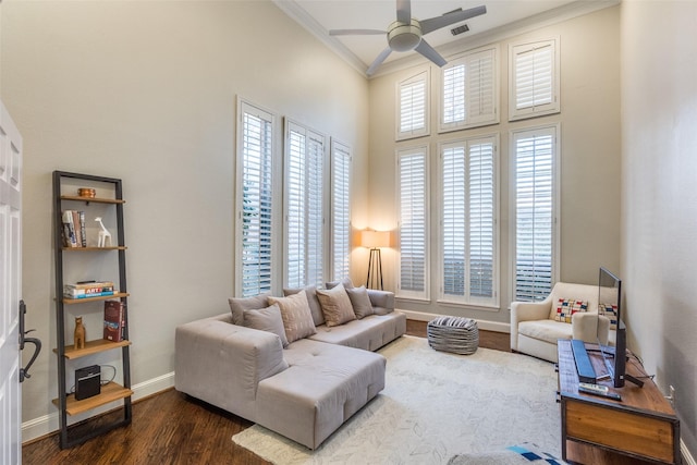 living area featuring a healthy amount of sunlight, crown molding, baseboards, and wood finished floors