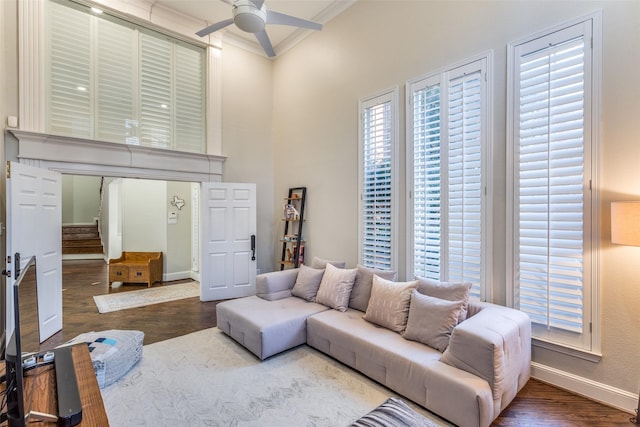 living area featuring ceiling fan, baseboards, stairway, ornamental molding, and wood finished floors