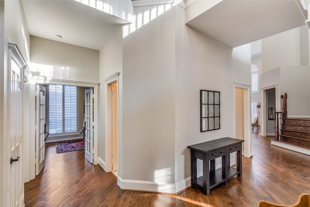 hall with stairway, baseboards, a high ceiling, and dark wood-style flooring