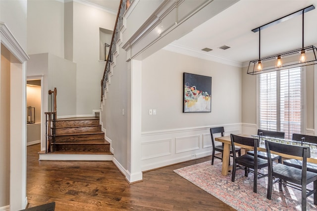 dining room with a wainscoted wall, dark wood-style floors, crown molding, and stairway