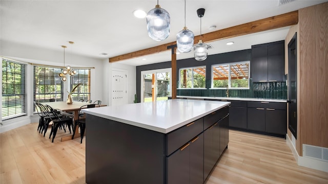 kitchen featuring light countertops, visible vents, light wood finished floors, and beam ceiling