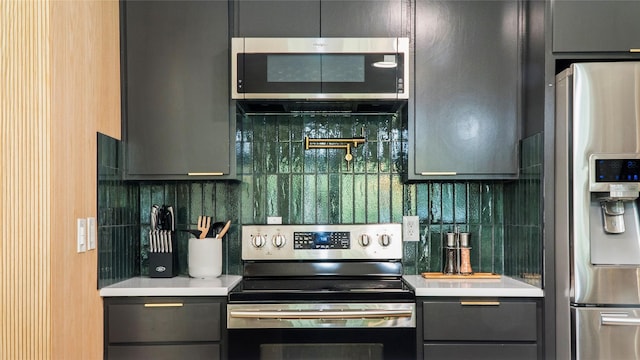 kitchen with stainless steel appliances, backsplash, gray cabinetry, and light countertops