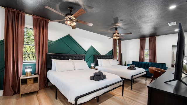 bedroom featuring visible vents, light wood-style floors, ceiling fan, and a textured ceiling