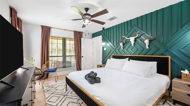bedroom featuring light wood finished floors, visible vents, and a ceiling fan