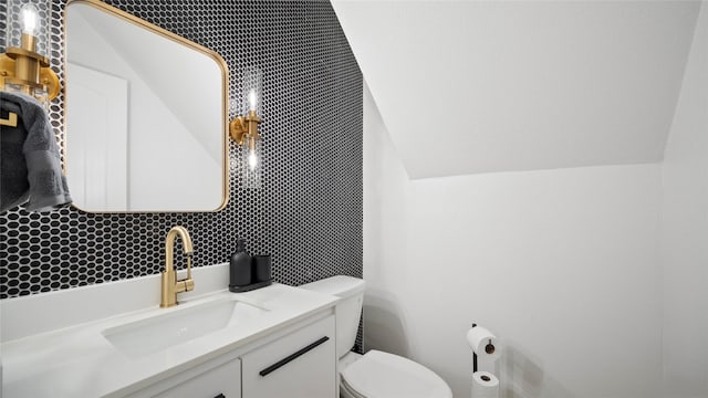 half bathroom featuring vanity, vaulted ceiling, and toilet