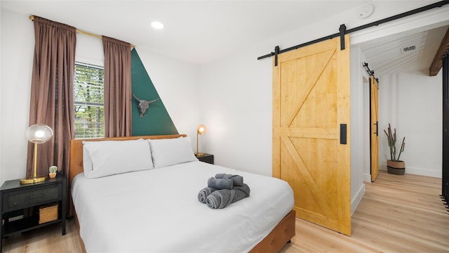 bedroom with visible vents, baseboards, recessed lighting, a barn door, and light wood-type flooring