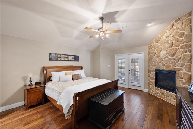 bedroom with baseboards, a fireplace, vaulted ceiling, hardwood / wood-style flooring, and access to outside