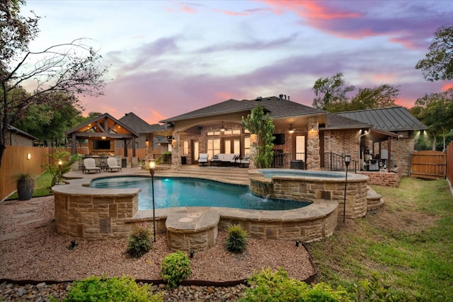 pool at dusk with a patio, a fenced backyard, a gazebo, an outdoor hangout area, and ceiling fan