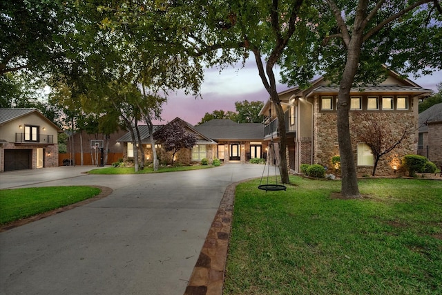 view of front of property featuring stone siding, curved driveway, a front yard, and a garage