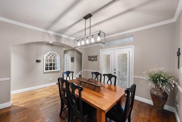 dining area with arched walkways, ornamental molding, baseboards, and wood-type flooring