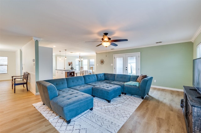 living area with light wood finished floors, baseboards, ornamental molding, ceiling fan with notable chandelier, and french doors