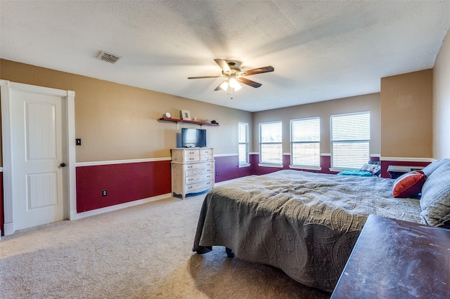 bedroom with visible vents, baseboards, carpet, a textured ceiling, and a ceiling fan