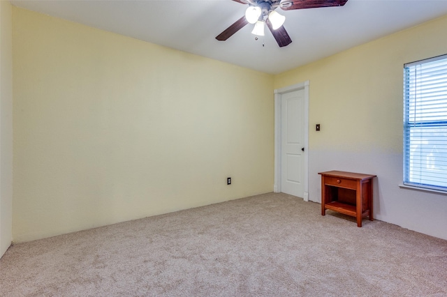 spare room with a healthy amount of sunlight, light colored carpet, and ceiling fan