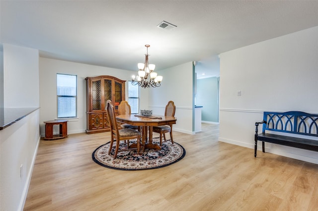 dining area featuring a chandelier, visible vents, baseboards, and light wood-style floors