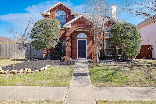 view of front of property featuring brick siding, a chimney, and fence