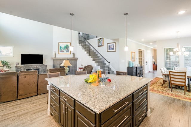 kitchen with light stone counters, open floor plan, light wood finished floors, and a chandelier