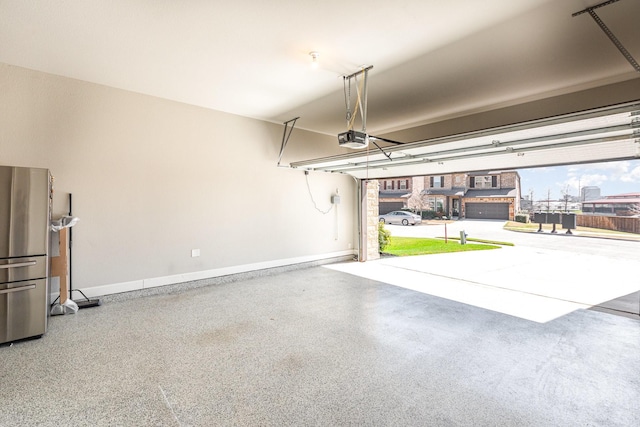 garage with a garage door opener, baseboards, and freestanding refrigerator