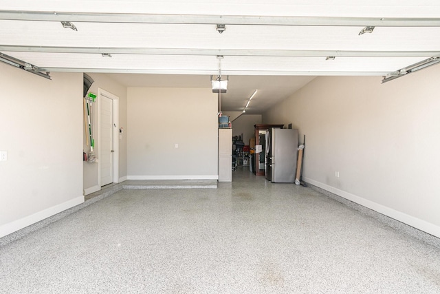 garage with a garage door opener, baseboards, and freestanding refrigerator