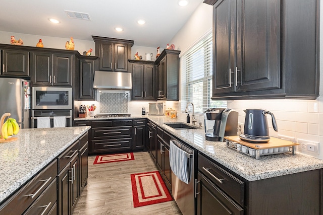 kitchen with visible vents, light wood-style flooring, stainless steel appliances, a sink, and under cabinet range hood