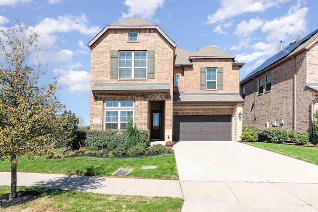 view of front of property with a front lawn, roof with shingles, concrete driveway, an attached garage, and brick siding