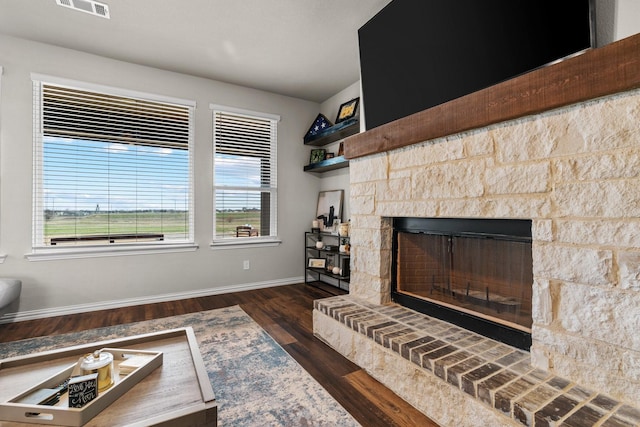 living room with a fireplace, visible vents, wood finished floors, and baseboards