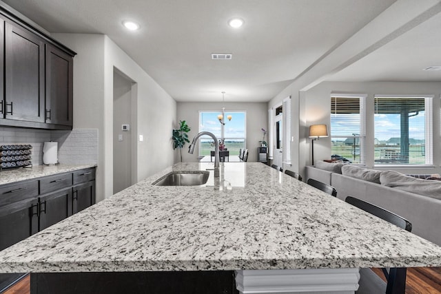 kitchen featuring visible vents, a sink, a large island, open floor plan, and tasteful backsplash