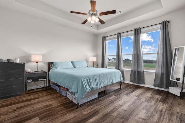 bedroom featuring wood finished floors, baseboards, visible vents, ceiling fan, and a raised ceiling