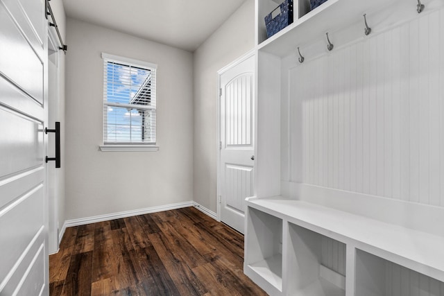mudroom with a barn door, baseboards, and dark wood-style flooring