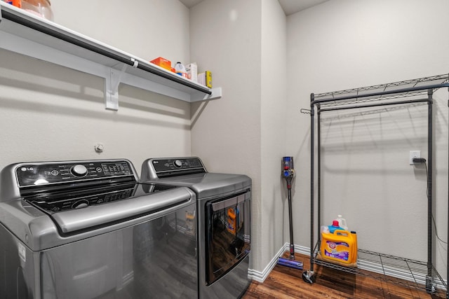 clothes washing area with baseboards, dark wood-type flooring, washing machine and dryer, and laundry area