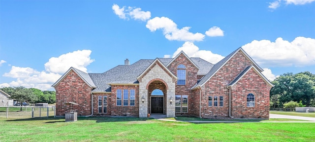 view of front of house with a front yard, fence, brick siding, and a chimney