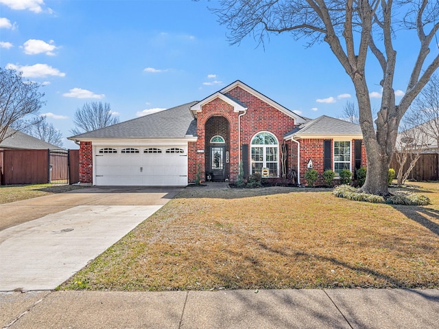 view of front facade with a front yard, fence, driveway, an attached garage, and brick siding