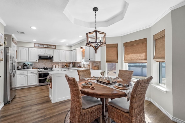 dining space featuring visible vents, crown molding, and wood finished floors