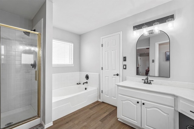 full bath with a bath, a shower stall, vanity, and wood finished floors