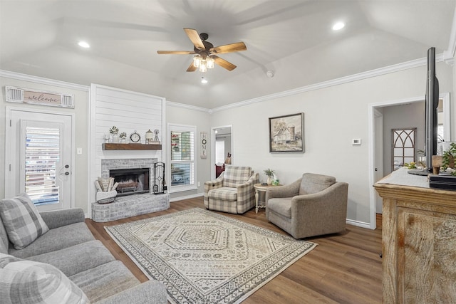 living room with a ceiling fan, wood finished floors, recessed lighting, a fireplace with raised hearth, and a raised ceiling