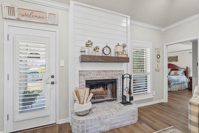 living area with crown molding, wood finished floors, a fireplace, and baseboards