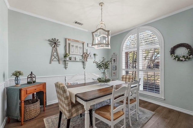 dining area featuring visible vents, wood finished floors, an inviting chandelier, wainscoting, and crown molding