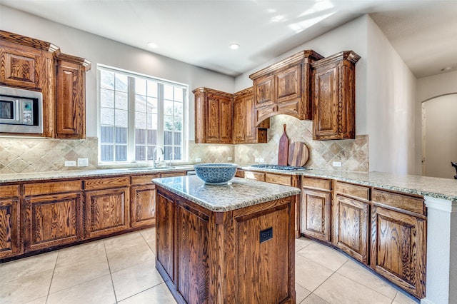 kitchen with light tile patterned flooring, a kitchen island, stainless steel appliances, and a sink