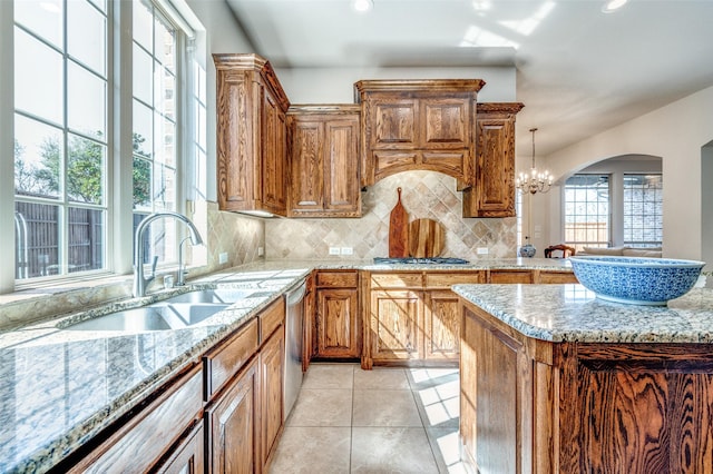 kitchen featuring arched walkways, backsplash, appliances with stainless steel finishes, and brown cabinetry