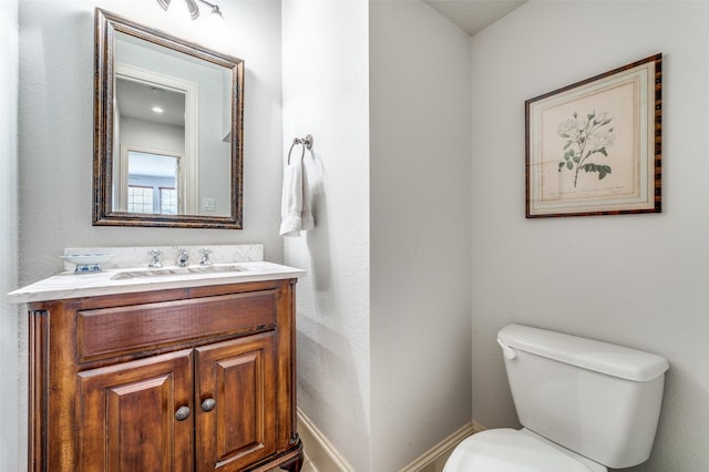 bathroom featuring baseboards, toilet, and vanity