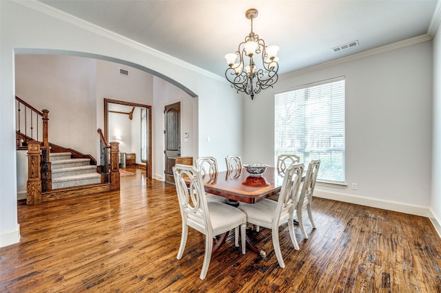 dining space featuring visible vents, ornamental molding, wood finished floors, arched walkways, and a chandelier