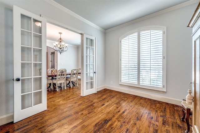 spare room featuring a notable chandelier, dark wood finished floors, french doors, crown molding, and baseboards